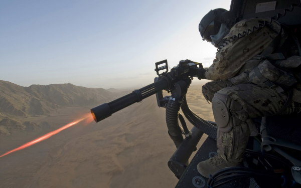 Солдат ведет стрельбу из пулемета с вертолета